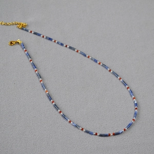Détail d'un collier fait main avec tubes de lapis-lazuli et fermoir mousqueton doré