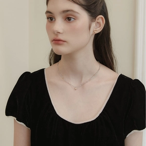 Detail of grey moonstone beaded necklace featuring a gold star pendant on female model