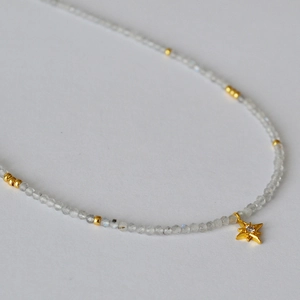 Macro shot of grey moonstone beaded necklace with a gold octagonal star pendant