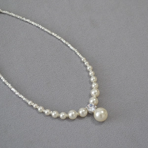 Elegant pearl and silver bead necklace featuring a high-luster central pearl pendant