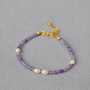 Detail view of faceted purple amethyst beads and white pearls on an elegant thin bracelet