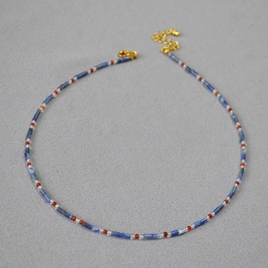 Détail du collier de perles en lapis-lazuli bleu et agate rouge avec fermoir mousqueton doré