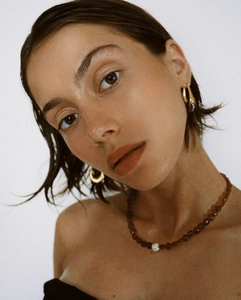 Gros plan d'un collier en perles d'agate rouge avec perle baroque et boucles dorées