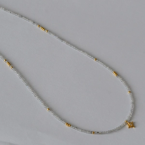 Detailed macro view of the grey moonstone beaded necklace and golden star charm