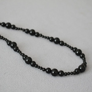 Macro detail of elegant black onyx beaded necklace with alternating polished gemstone sizes
