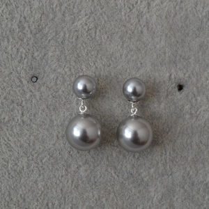 Detail of elegant double grey pearl earrings with silver posts on a textured background