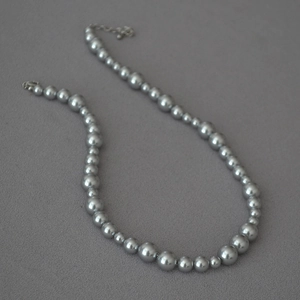 Detail of silver gray pearl necklace featuring a gradient bead size design on fabric