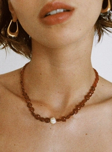 Détail du collier de perles en agate rouge avec perle baroque et boucles d'oreilles dorées