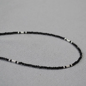 Makroaufnahme minimalistischer 2mm facettierter schwarzer Spinellperlen mit Silberakzenten
