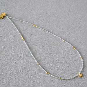 Macro detail of a gray moonstone beaded necklace with a gold star pendant and lobster clasp