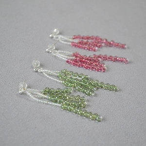 Close-up of handmade beaded tassel earrings in pink and green with silver pins