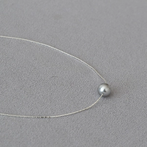 Macro shot of a sleek grey pearl pendant on a minimalist silver chain for women