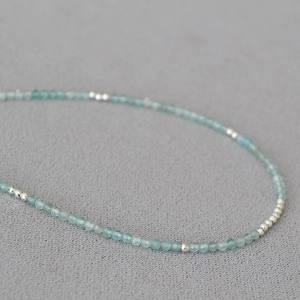 Macro shot of minimalist aquamarine beaded necklace with faceted light blue stones and silver