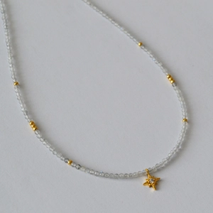 Macro shot of grey moonstone beads necklace with a sparkling gold star pendant detail