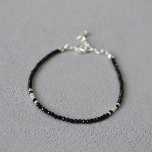 Detailed macro view of minimalist black beaded bracelet with silver lobster clasp