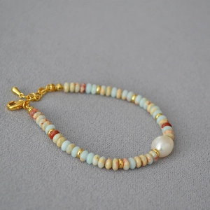 Handmade necklace with blue and brown stone beads featuring a large white pearl and gold accents