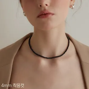Dettaglio di una collana di perle di onice nera da 4mm indossata da una modella elegante