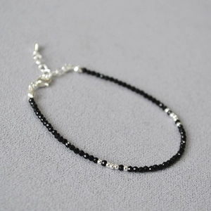 Macro detail of natural black gemstone beads with silver accents and lobster clasp chain