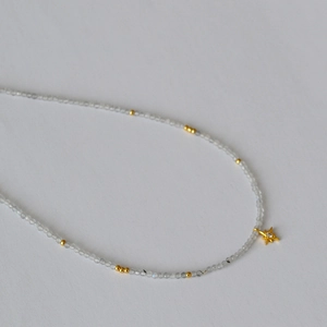 Macro shot of grey moonstone beaded necklace with a sparkling gold star pendant detail