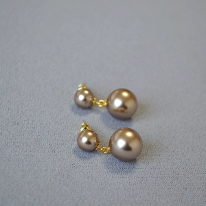 Detailed view of elegant double champagne pearl earrings on a blue fabric background
