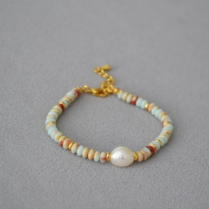 Detail of beaded necklace with blue natural stones and large white baroque pearl accent