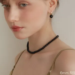 Dettaglio della collana di perle di agata nera da 6mm e orecchini a cerchio in oro