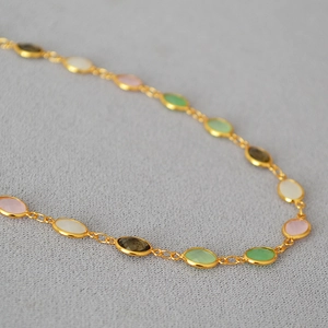 Detail of gold necklace with multi-color oval crystals and elegant metal edging