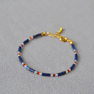 Detailed close-up of beaded bracelet with blue stone tubes and gold adjustable clasp