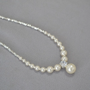 Detail of beaded pearl necklace with silver accents and a sparkling zircon pendant