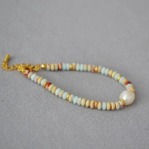 Detailed macro view of beaded bracelet with natural blue stones and freshwater pearl