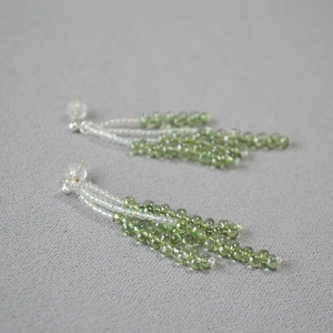 Macro view of crystal beaded tassel earrings featuring green gradient berry clusters