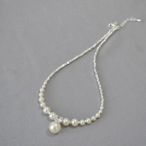 Detailed view of high-lustre pearl necklace with a central zircon and silver beads