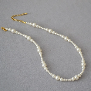Detail of elegant pearl necklace featuring alternating sizes and golden adjustable clasp
