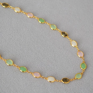 Detailed macro view of multi-color oval crystals on a gold-plated brass chain necklace