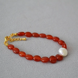 Détail de perles d'agate rouge et perle baroque avec fermoir doré et chaîne d'extension
