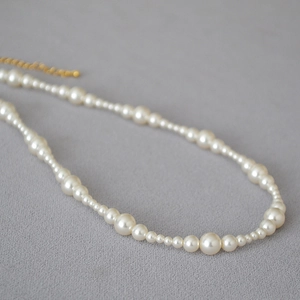 Macro shot of elegant cream pearls and golden lobster clasp detail on minimalist necklace
