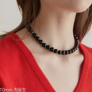 Dettaglio della collana di onice nero da 10mm indossata su una modella con maglia rossa
