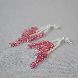 Macro shot of pink crystal beaded fringe earrings with 925 silver needles on grey fabric