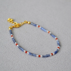 Detail of beaded bracelet with blue stones, red accents and golden lobster clasp