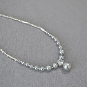 Macro detail of gray pearls and silver beads necklace with a center zircon crystal pendant