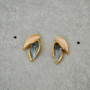 Detail of leaf-shaped brass earrings with pink and grey marble texture enamel inlay