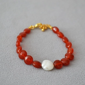 Vue macro détaillée des perles d'agate rouge et d'une perle baroque sur un fermoir doré