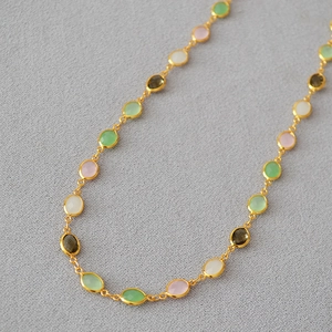 Close-up of a gold-plated necklace featuring oval colorful crystals and glass stones