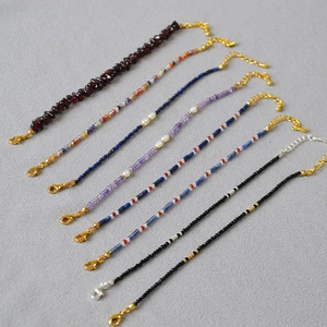 Detail view of seven natural stone and freshwater pearl beaded bracelets with metal clasps