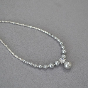 Detail of gray gradient pearls and faceted silver beads with central sparkling zircon stone