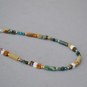 Bohemian multicolored natural stone beaded necklace with gold metal spacers on grey fabric