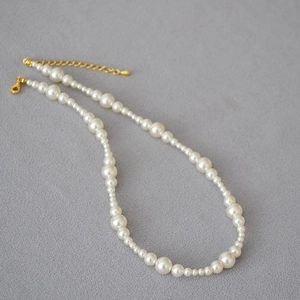 Detailed close-up of white round pearls with a gold lobster clasp and adjustable chain