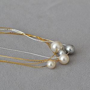 Macro shot of minimalist multi-layered gold and silver wire necklace with pearls