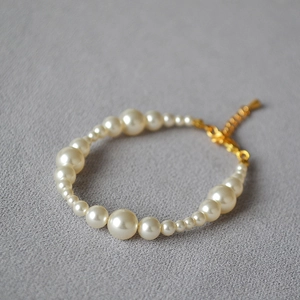 Detail of elegant pearl bracelet with varied bead sizes and golden adjustable chain clasp