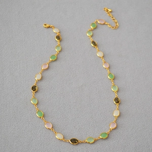 Detail of gold plated necklace featuring colorful faceted crystal and oval resin beads